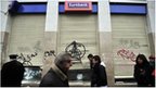 People walk past a damaged Eurobank branch in central Athens on February 13